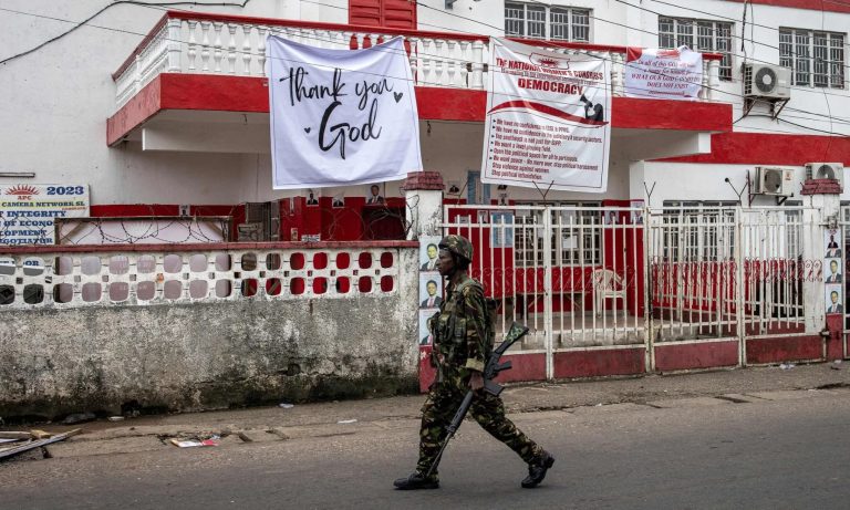 A soldier walks past APC headquarters in Freetown, Sierra Leone.
