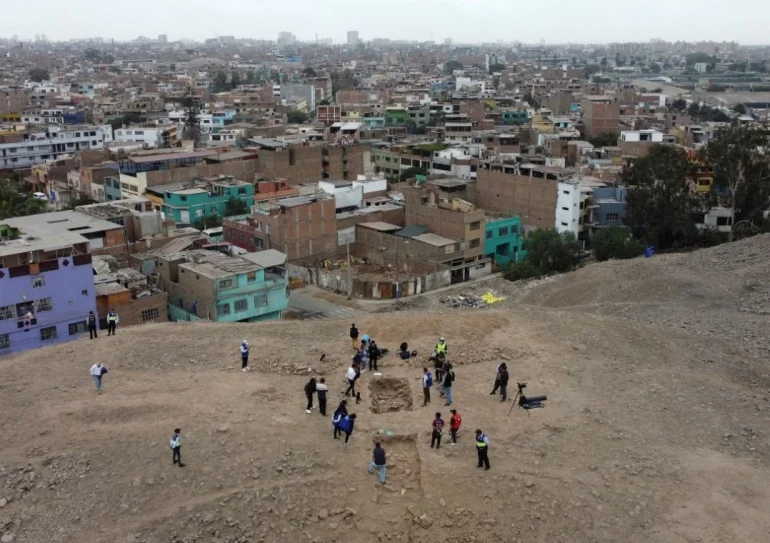 A group of individuals stands near the excavation site of a pre-Hispanic burial, captivated by the presence of a mummy attributed to the Manchay culture. This mummy, dating back to the period between 1,500 and 1,000 BCE, serves as a tangible connection to the ancient heritage of Lima, Peru.