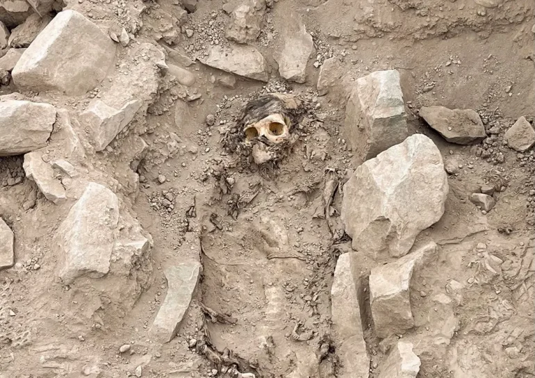 The photo captures the well-preserved remains of a mummy, believed to originate from the Manchay culture that thrived in the Lima valleys between 1,500 and 1,000 BCE. The mummy lies amidst the excavation site of a pre-Hispanic burial, offering a glimpse into the ancient history of Lima, Peru.